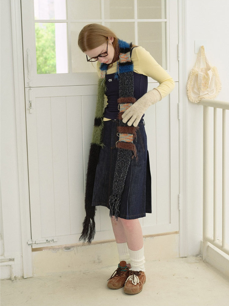 Woman adjusting her long, textured scarf with fringe details.