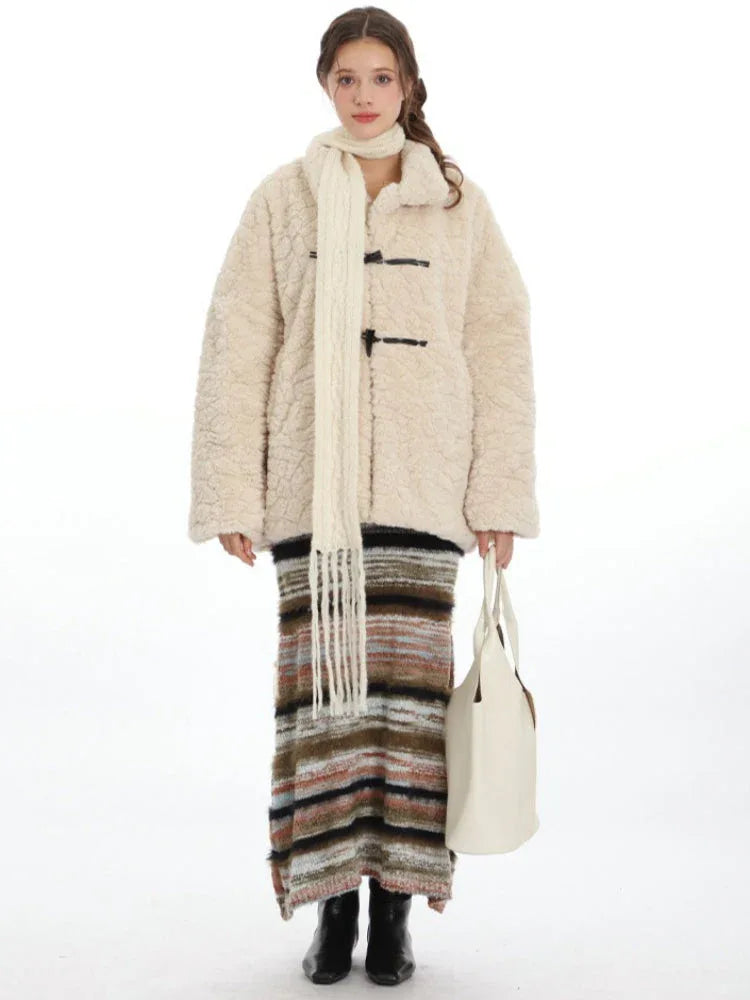 Woman wearing a cream-colored fleece coat with toggle closures, a cream scarf, a striped maxi skirt, and a white tote bag, front view. Main image