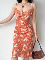 Woman adjusting her floral print midi slip dress, showing the flowy hem.