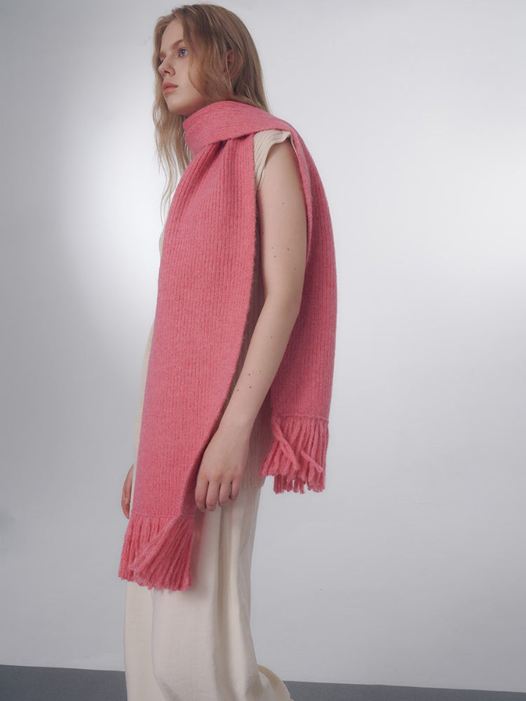 Side view of a model showcasing a long pink knitted scarf with fringe. Secondary image