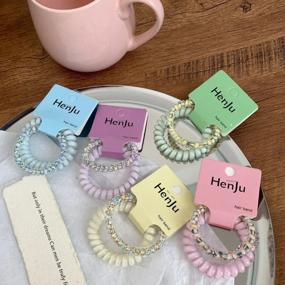 Various pastel spiral hair ties with beaded embellishments, shown on a silver platter.
