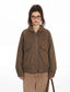 Close-up of a woman wearing a brown bomber jacket and tan pants.