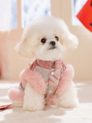White fluffy dog wearing a pink and green traditional Chinese-style coat with faux fur trim