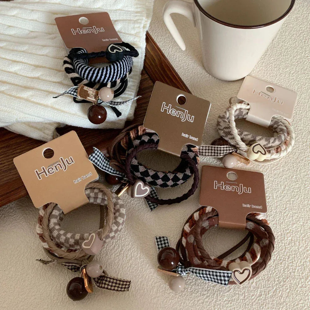 A variety of Henju hair ties arranged on a table with a white knitted item and a mug.
