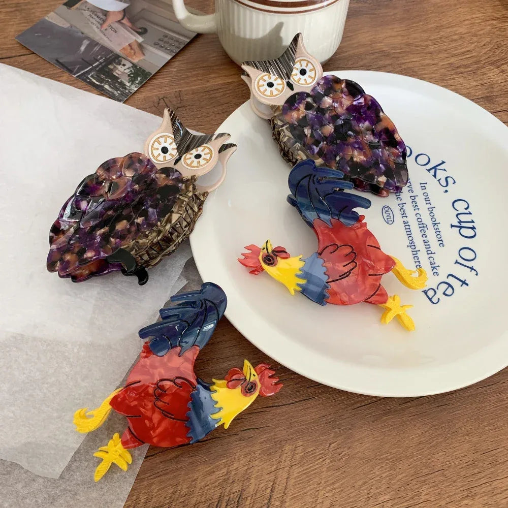 Two acrylic owl hair clips and two acrylic rooster hair clips arranged on a plate