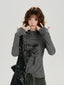 Woman wearing a grey long-sleeve graphic print turtleneck top with thumbhole cuffs and a drawstring hem.
