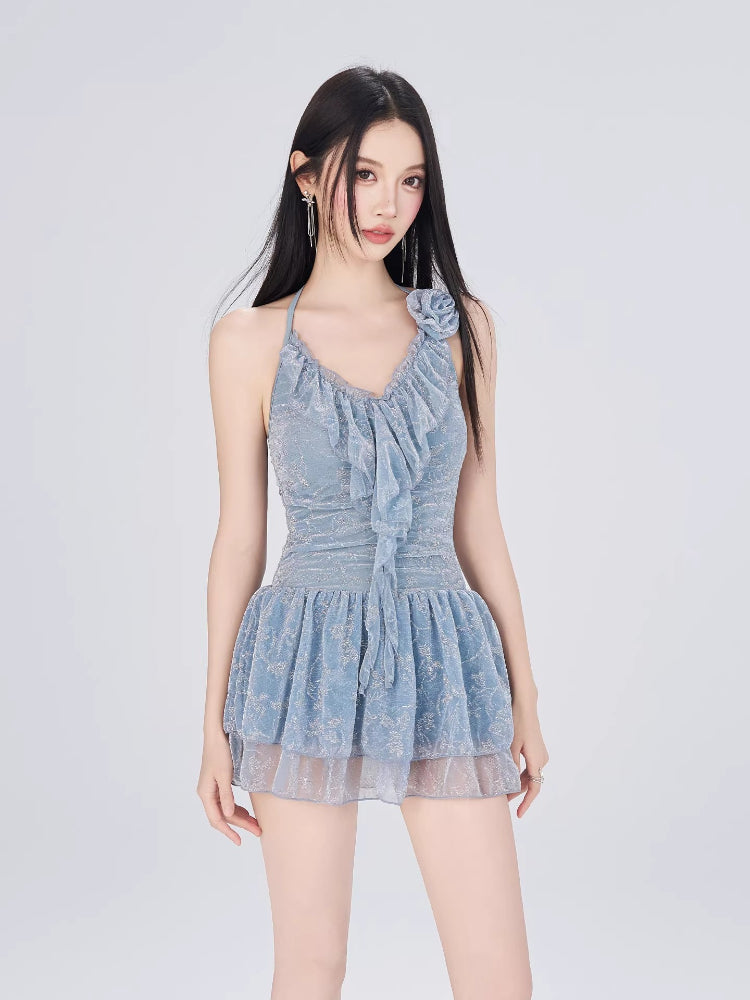 Woman in a light blue ruffled halter dress, front view, with hair blowing.