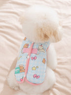 Rear view of a white poodle wearing a light blue gingham dog vest with cartoon bears and strawberries