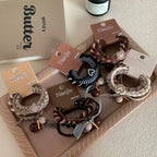 A set of Henju hair ties presented on a tray, alongside a book and a bottle.