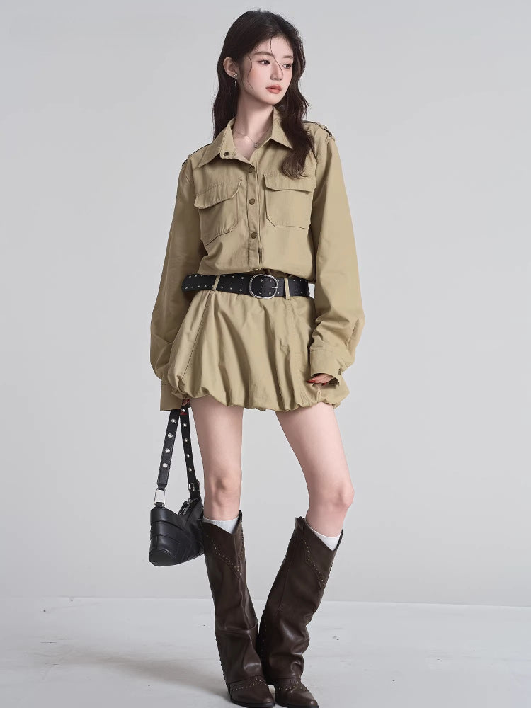 Full body shot of a model in a tan shirt dress with a gathered skirt, black belt, and knee-high boots.