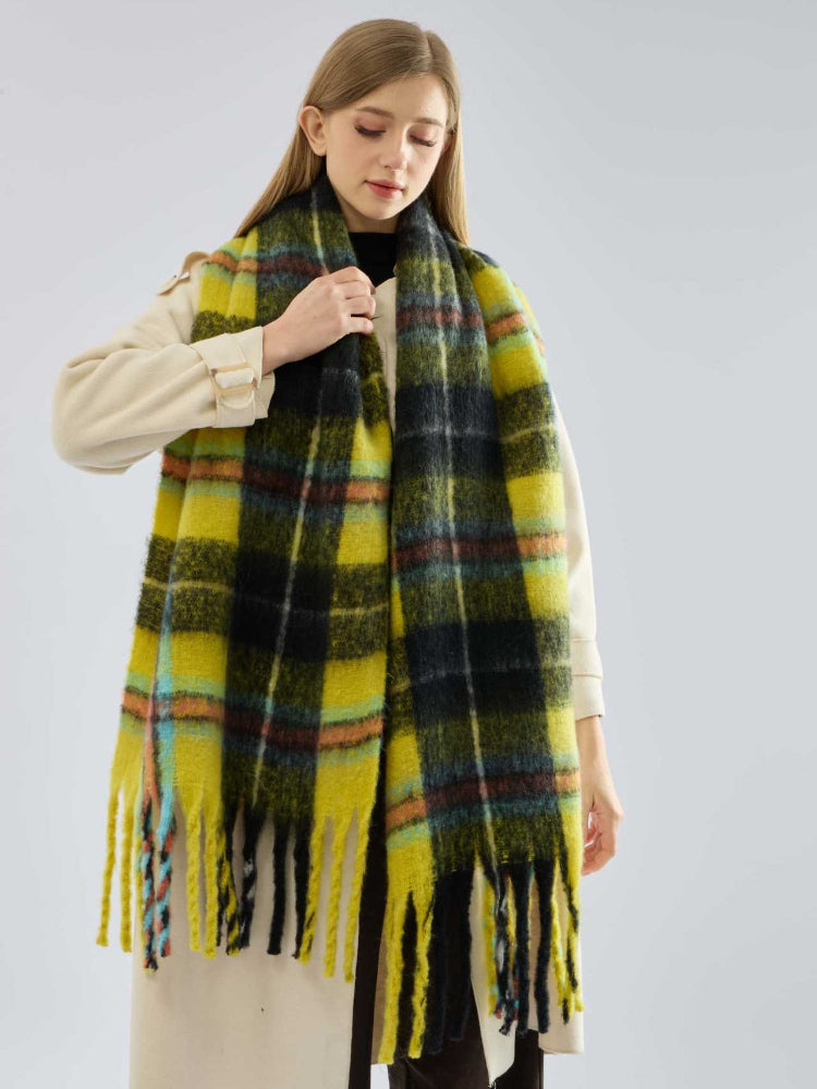 Woman adjusting her yellow and black plaid scarf over a cream coat.