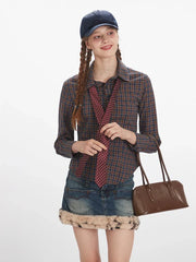 Front view of a woman holding a tie to her chest, wearing a plaid button-down shirt, denim mini skirt with faux fur trim, and a handbag.