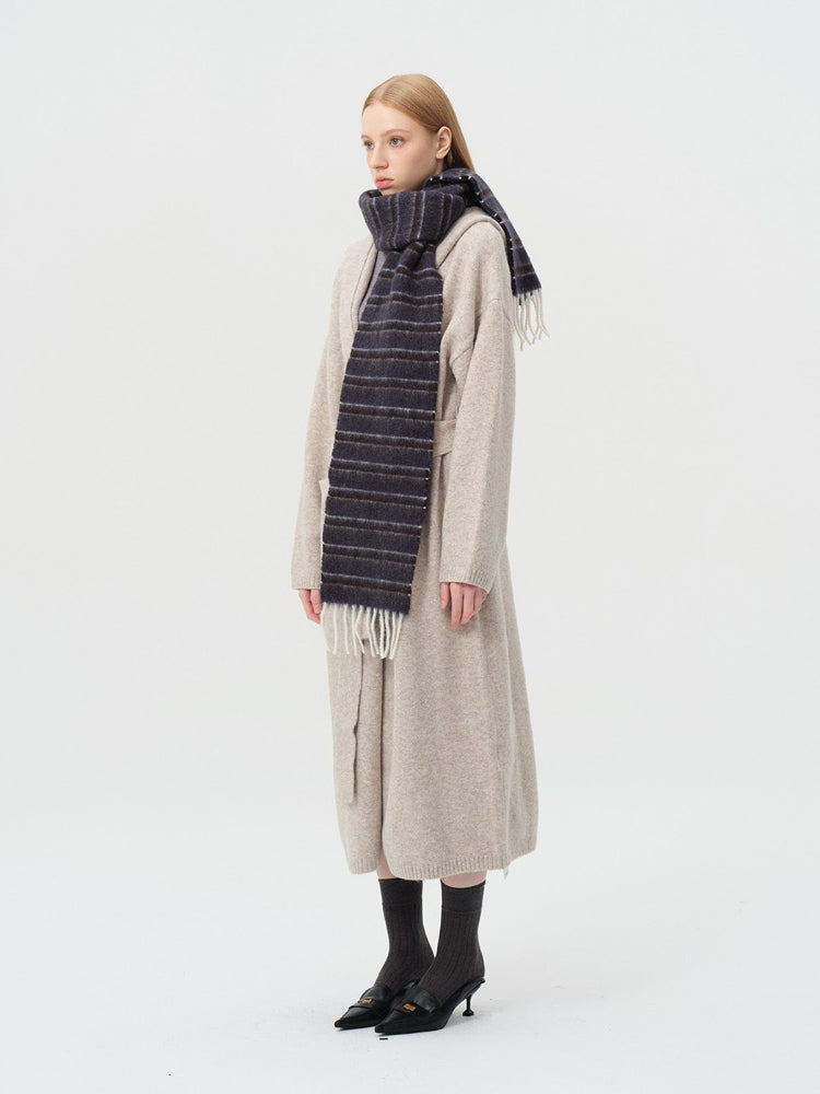 model wearing a beige cardigan and a dark striped scarf from the side