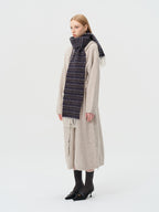 model wearing a beige cardigan and a dark striped scarf from the side