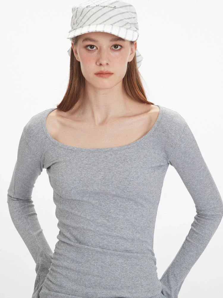 Close-up front view focusing on the neckline and upper chest of a woman wearing a grey long-sleeve ribbed knit top.