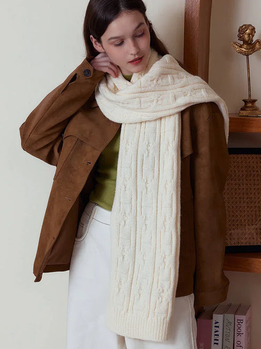 Close-up of a woman wearing a cream-colored cable knit scarf.