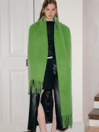 Full body shot of a woman wearing a bright green oversized scarf with fringed ends