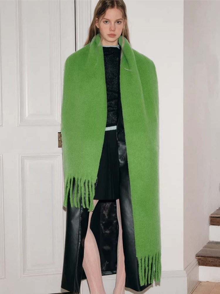 Full body shot of a woman wearing a bright green oversized scarf with fringed ends