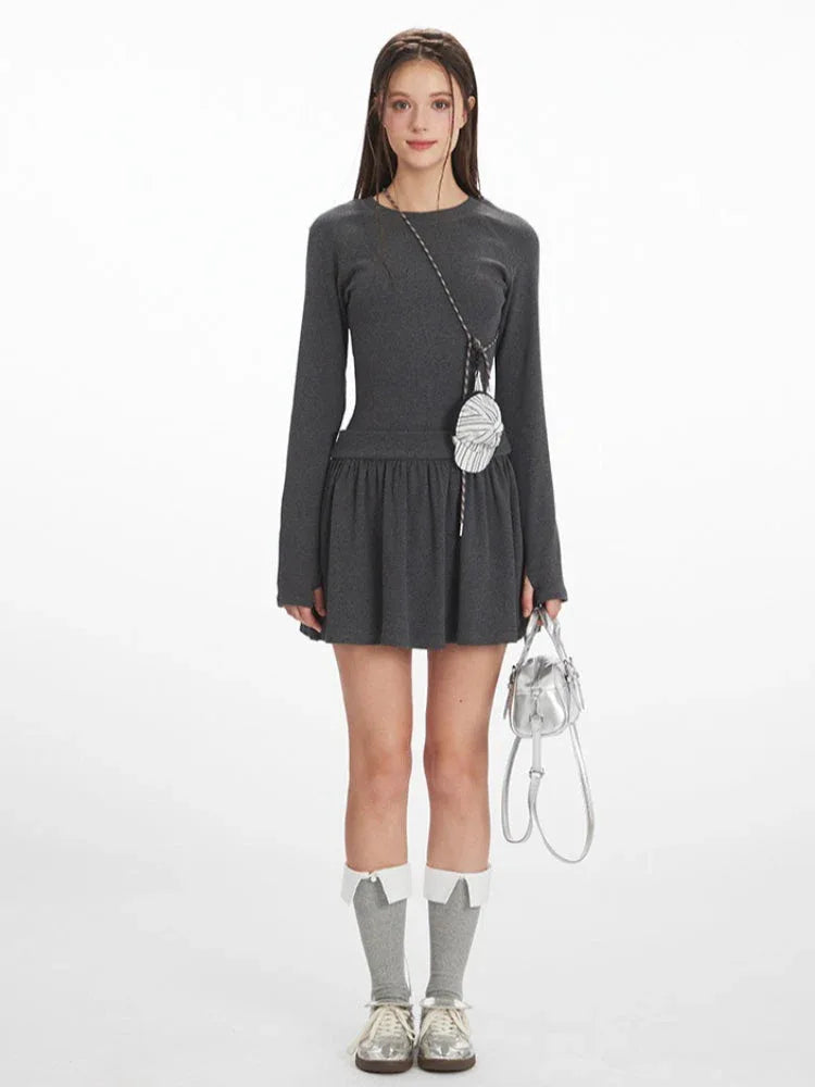 Woman wearing a dark grey long-sleeve mini dress with a gathered waist, white-trimmed grey socks, and silver shoes, holding a silver handbag and a small striped pouch around her neck. Main image