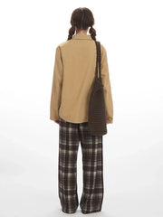 Back view of a model wearing a tan button-down shirt and brown plaid wide-leg pants.