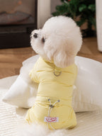 Side view of a white bichon frise dog in a yellow puffer coat, sitting on a pillow
