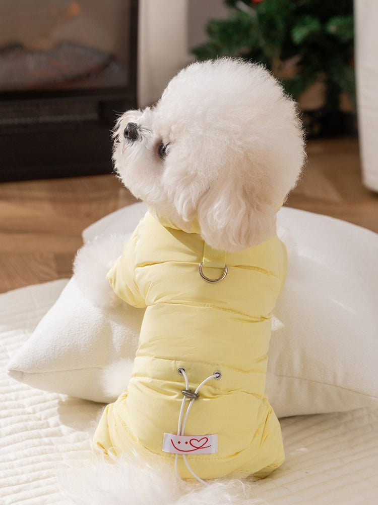Side view of a white bichon frise dog in a yellow puffer coat, sitting on a pillow