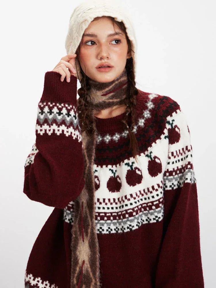Close-up of a woman wearing a maroon and white knit sweater with an apple Fair Isle pattern, showing the texture of the knit and the details of the pattern.