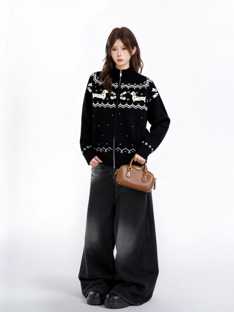 Full body shot of a woman wearing a black zip-up knit sweater with a white fair isle dog pattern and wide-leg black jeans.