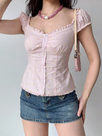 Woman wearing a pink striped and floral print top with a denim mini skirt and a pink shoulder bag.