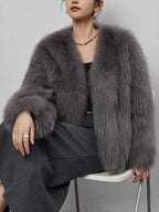 Woman sitting down wearing a grey faux fur cropped jacket.