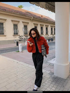 Woman wearing a red fur jacket and black pants walking down a street