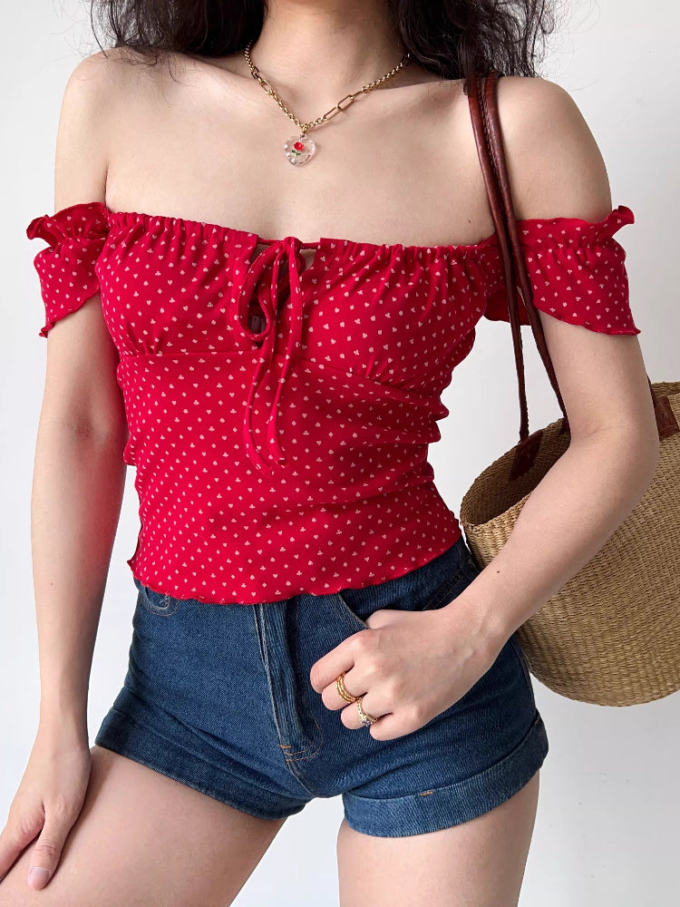 Woman wearing a red off-the-shoulder top with a heart print and denim shorts