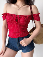 Woman wearing a red off-the-shoulder top with a heart print and denim shorts