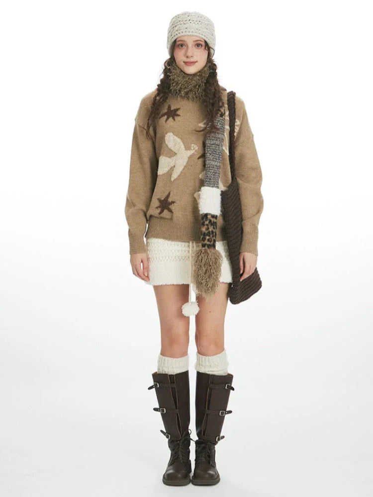 Front view of a woman wearing a brown sweater with a bird and star pattern, a white textured skirt, cream leg warmers, and brown boots. Main image