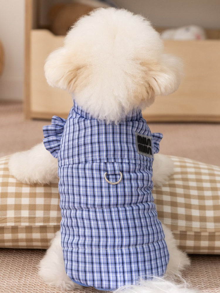 The back of a white dog wearing a blue plaid dog vest, showing the d-ring and logo detail.