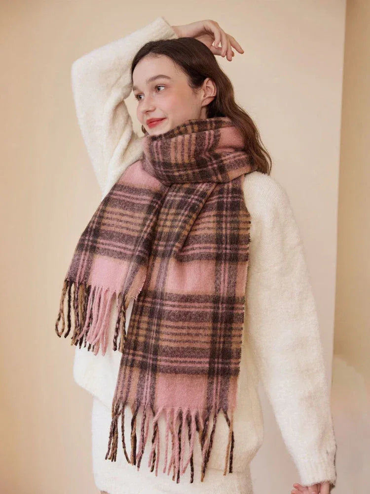 Model wearing a pink and brown plaid scarf with fringe
