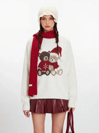Close-up of a white fuzzy knit sweater with a graphic of two teddy bears wearing Christmas hats.