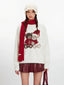 Close-up of a white fuzzy knit sweater with a graphic of two teddy bears wearing Christmas hats.