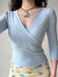 Close-up of a light blue wrap-style top with a V-neck and three-quarter sleeves.