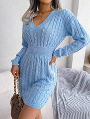 woman in a light blue cable knit dress holding a handbag