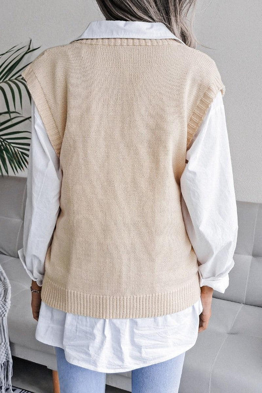 Back view of a woman wearing a cream knit V-neck sleeveless vest over a white collared shirt.
