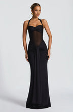 Woman wearing a black floor-length halter gown with a sheer midriff and ruched skirt