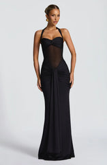 Woman wearing a black floor-length halter gown with a sheer midriff and ruched skirt