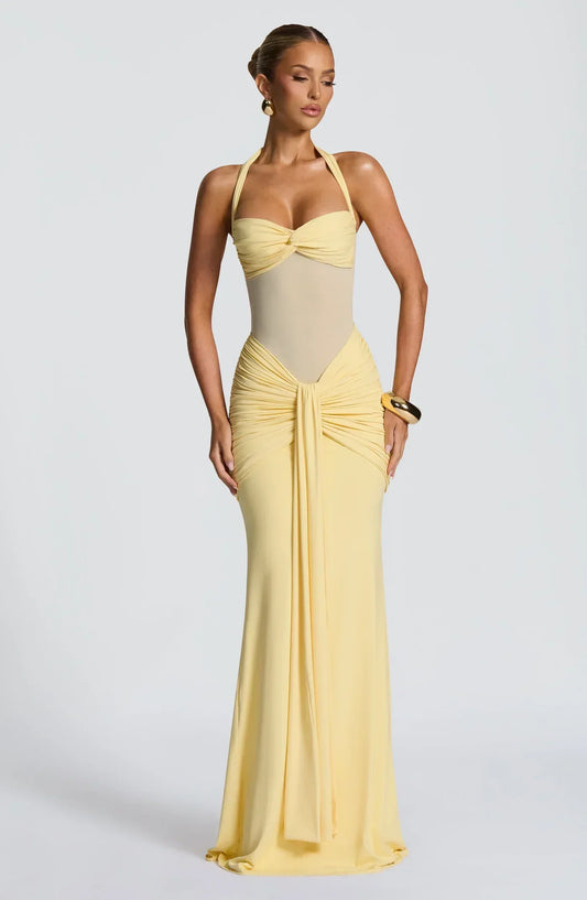 Woman wearing a pale yellow floor-length halter gown with a twisted bodice and ruched skirt