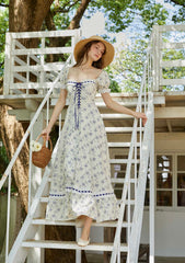 Woman wearing a cream floral print midi dress with puff sleeves and a square neckline on outdoor stairs.