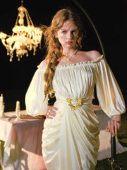 Close-up of a woman in a cream satin dress with an off-the-shoulder neckline and puffy sleeves, featuring a gold belt buckle.