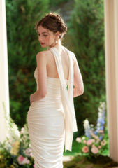 A woman poses in a cream satin mermaid dress, highlighting the elegant draping and off-the-shoulder design.