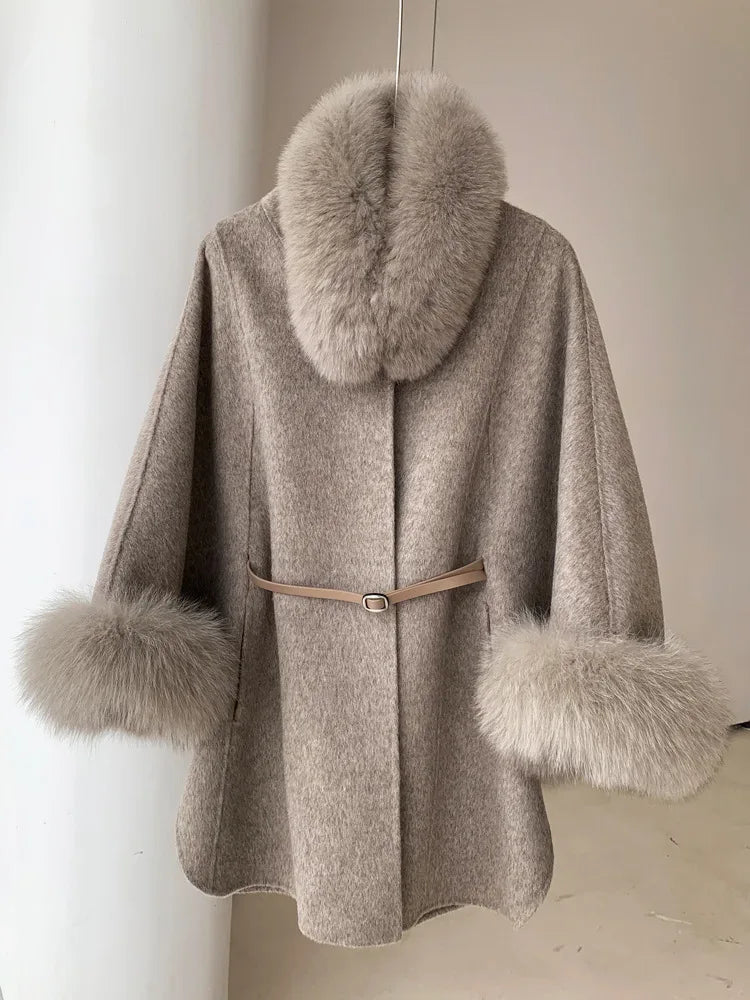 Light grey wool blend cape with fur collar and cuffs, cinched with a belt, hanging on a rack