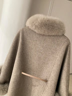 Close-up of the back of a light grey wool blend cape with fur collar and belt detail