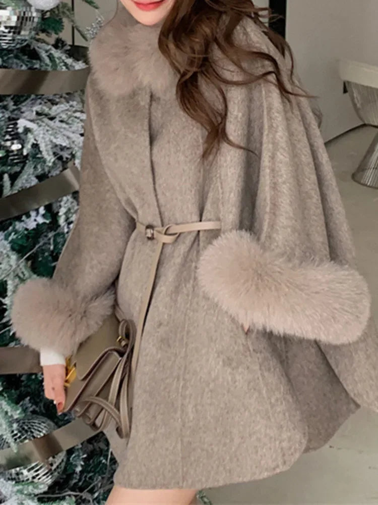 Light grey wool blend cape with fur collar and cuffs, cinched with a belt, worn by a person